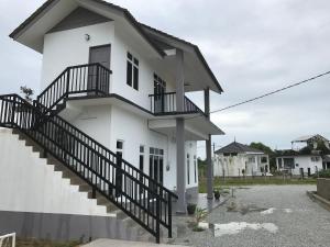 une maison blanche avec un escalier en face de celle-ci dans l'établissement Rumah Sawah Homestay Pasir Puteh, à Pasir Puteh