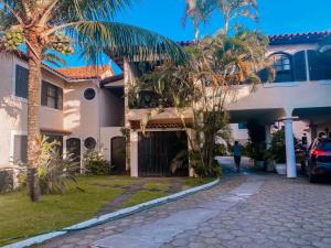 a person walking past a house with palm trees at Casa Vila da Praia Buzios - Centro in Búzios