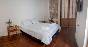 a bedroom with a large white bed and a wooden floor at Hotel Casa Allegra Art Suites in Rosario