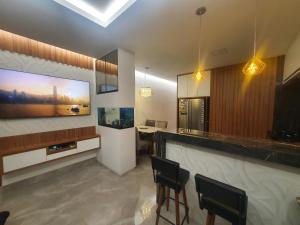 a kitchen with a bar with chairs and a tv at Residencial Goulart in Capitólio