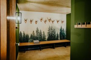 un banc dans une pièce ornée d'une fresque murale représentant des arbres dans l'établissement Alpenrose Bayrischzell Hotel, à Bayrischzell