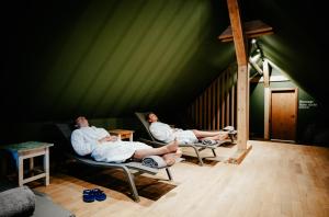3 Männer sitzen auf Stühlen in einem grünen Zimmer in der Unterkunft Alpenrose Bayrischzell Hotel in Bayrischzell