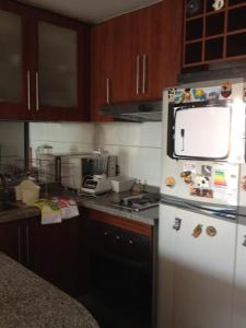 a kitchen with a white refrigerator with magnets on it at ACOGEDOR DEPARTAMENTO EN APOQUINDO in Santiago