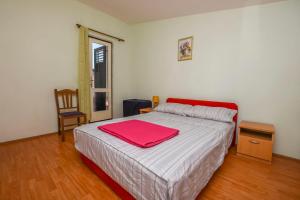 una camera da letto con un letto con una coperta rossa sopra di Apartment Vlatka a Rogoznica (Rogosnizza)