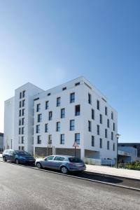 deux voitures garées devant un bâtiment blanc dans l'établissement Appart'City Classic Rennes Beauregard, à Rennes