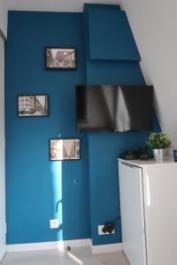 a room with a blue wall with a tv at Paris 17 - Batignolles - Studio 10 m2 - 1 room - Single occupancy - near Champs Elysées & Montmartre & Dpt stores in Paris