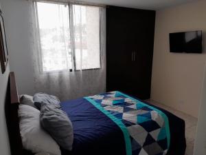1 dormitorio con 1 cama con edredón y ventana en Apartamento de lujo Edif. El Fortin, en Guayaquil
