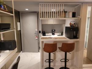 a small kitchen with two bar stools and a counter at Hotel Bourbon Ibirapuera Suite 5 estrelas Moema in Sao Paulo