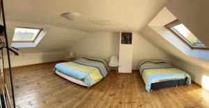two beds in a attic bedroom with two windows at GRANDE MAISON COZY, SUD, 15 MIN SPA FRANCORCHAMPS in Theux