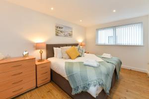 a bedroom with a bed and a dresser and a window at Just Stay Wales - Meridian Wharf, Marina View - 2 Bed Apartment in Swansea