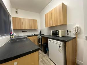 uma cozinha com armários de madeira e um balcão preto em Nice Living Serviced Accommodations 3 em Coventry