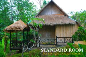 a small house with a straw roof in a forest at Pai Vintage Garden Resort in Pai