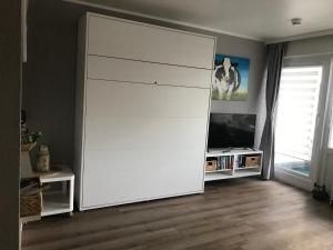 einen großen weißen Schrank im Wohnzimmer mit einem TV in der Unterkunft Haus Westerhörn am Strand in Westerland