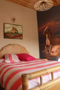 a bedroom with a bed with a painting of a horse on the wall at La Petite Bérais in Missillac