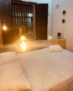 ein Schlafzimmer mit einem großen weißen Bett mit einer Lampe in der Unterkunft Hostal 1545 in Ríohacha