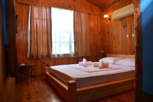 a bedroom with a large bed with a window at Tahtavilla Pansiyon in Cıralı