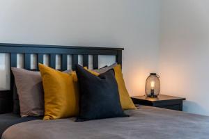 a bed with yellow and black pillows and a lamp at Initial / Lagom / MSA in Saint-Férréol-les-Neiges