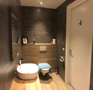 La salle de bains est pourvue de toilettes blanches et d'un lavabo. dans l'établissement Bed no breakfast de Kapitein, à 't Horntje