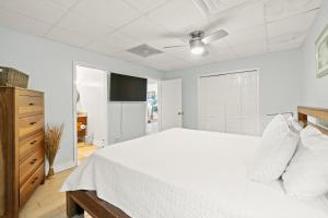 a white bedroom with a bed and a tv at Sans Souci 407 in Pensacola Beach