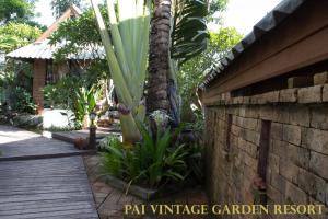 a wooden walkway next to a house with a palm tree at Pai Vintage Garden Resort in Pai