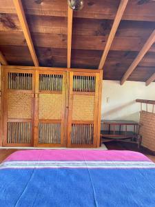Habitación con cama con paredes de madera y techos de madera. en Casita Monarca, en Troncones