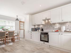 a kitchen with white cabinets and a table with chairs at Pennyard House in Banwell