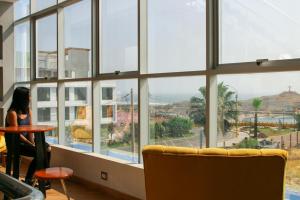 una mujer sentada en una mesa frente a una gran ventana en Hotel Las Terrazas De Caral, en Barranca