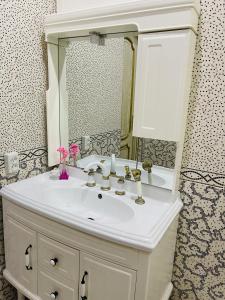 een badkamer met een witte wastafel en een spiegel bij Aleksandra Apartment in Samarkand