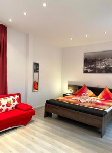 a bedroom with a bed and a red chair at Hotel Martz in Pirmasens