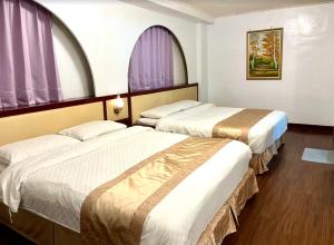 two beds in a hotel room with purple windows at Inn Sun Hotel in Changhua City
