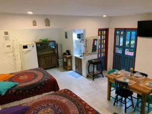 a room with a bed and a table and a kitchen at Apartamento Color Centro Histórico - Vila Ilhabela in Ilhabela