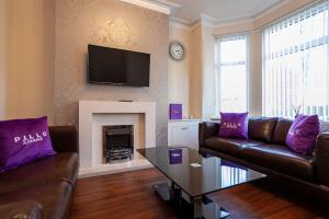 a living room with a couch and a fireplace with purple pillows at Pillo Rooms - Spacious Cosy 2 Bedroom House by Bridgewater Canal in Manchester