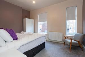 a bedroom with a bed and a chair and two windows at Pillo Rooms - Spacious Cosy 2 Bedroom House by Bridgewater Canal in Manchester