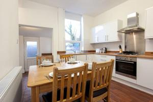 una cocina con mesa de madera y sillas. en Pillo Rooms - Spacious Cosy 2 Bedroom House by Bridgewater Canal en Mánchester