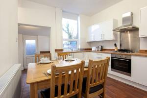 a kitchen with a wooden table and chairs in it at Pillo Rooms - Spacious Cosy 2 Bedroom House by Bridgewater Canal in Manchester