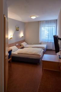 a hotel room with two beds and a television at Hotel Restaurant Lindenhof in Biblis