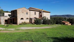 a large stone house with a green field in front of it at Enrica - Agriturismo La Valentina in Talamone
