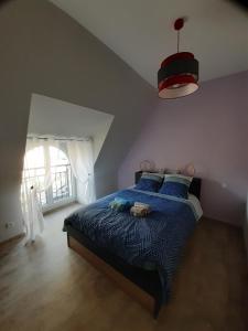 1 dormitorio con 1 cama con edredón azul y ventana en gite de La Carrière, en Saint-Julien-de-Piganiol