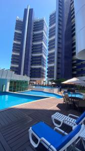 a swimming pool with lounge chairs and some buildings at Apartamento Beira Mar Fortaleza Beach Class in Fortaleza