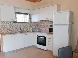 a kitchen with white cabinets and a white refrigerator at Angela's place - Stomio residence near the sea in Stómion