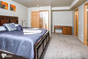 a bedroom with a bed with blue sheets and a table at Tranquil Stay at Settlers Bay, Newly Furnished! in Wasilla