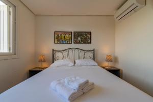ein Schlafzimmer mit einem großen weißen Bett mit Handtüchern darauf in der Unterkunft Residencial Alegro - 301 in Canela
