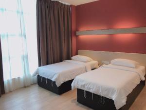 two beds in a hotel room with red walls at Tras Mutiara Hotel Bentong in Bentong