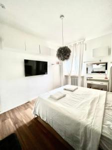a white bedroom with a bed and a flat screen tv at white home near Linate in Segrate