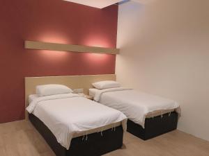 two beds in a room with red walls at Tras Mutiara Hotel Bentong in Bentong