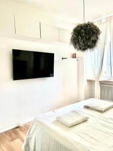 a white bedroom with a flat screen tv on a wall at white home near Linate in Segrate