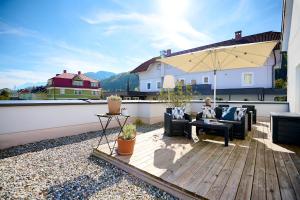 a patio with chairs and an umbrella on a balcony at Wallner - Hotel & Wirt in Arnoldstein
