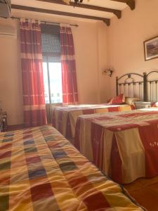 a hotel room with two beds and a window at Hotel Meson Fuente del Pino in Olvera