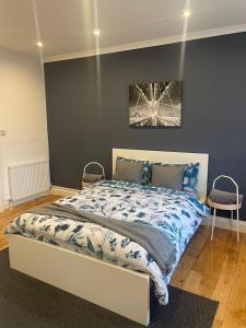 a bedroom with a bed with a blue wall at Wembley Rooms in London