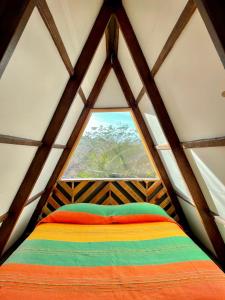 Bett in einem Zimmer mit einem großen Fenster in der Unterkunft Glamping Tepeyollotl in Troncones